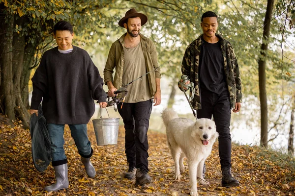 Los hombres caminan con perro y equipo de pesca en la naturaleza — Foto de Stock
