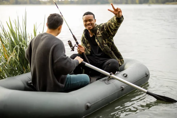 Amis mâles pêchant sur un bateau en caoutchouc dans la rivière — Photo