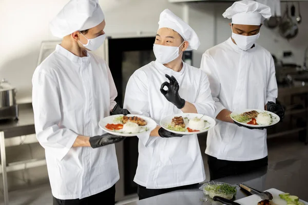 Multiraciale team van koks staan met kant-en-klare maaltijden voor een restaurant in de keuken — Stockfoto