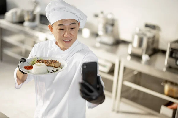 Chef asiático gravar um vlog culinária no telefone na cozinha — Fotografia de Stock