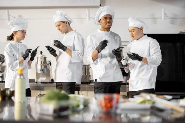 Equipe de cozinheiros multirraciais conversando durante uma pausa para café na cozinha — Fotografia de Stock