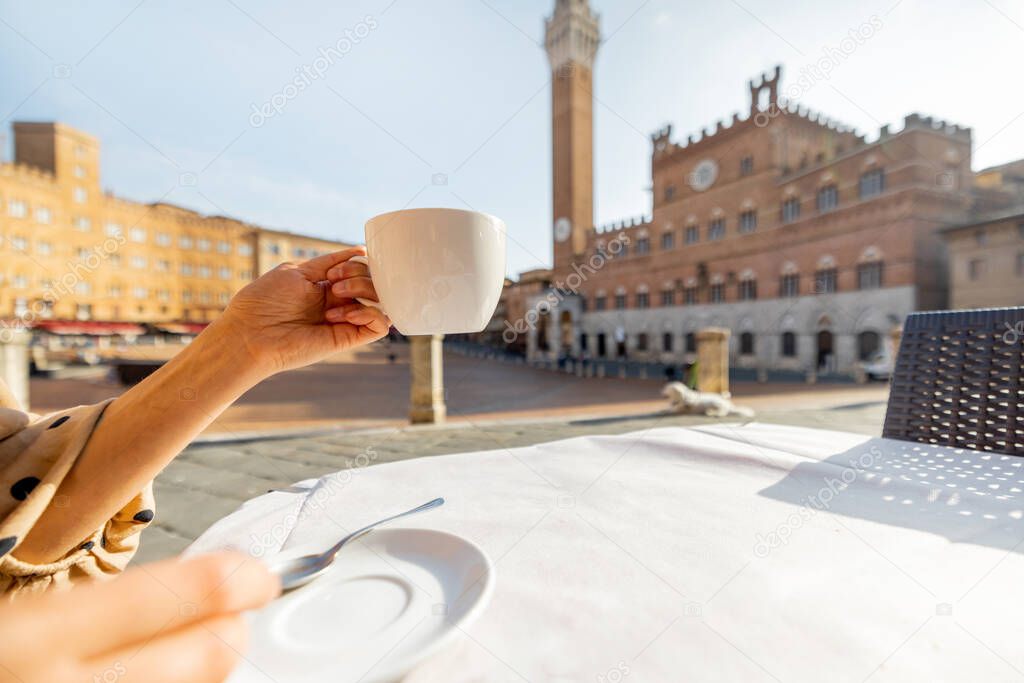 Drinking coffee at outdoor cafe on a main square of Siena city in Italy