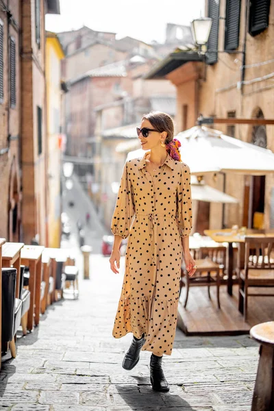 Mujer elegante camina por la calle estrecha y acogedora en el casco antiguo de la ciudad de Siena —  Fotos de Stock