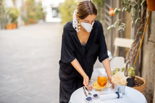 Mulher tira máscara facial enquanto se senta no restaurante italiano ao ar livre — Fotografia de Stock