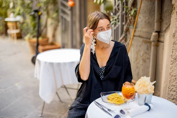 Kvinna tar av ansiktsmask medan du sitter på italiensk restaurang utomhus — Stockfoto