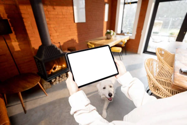 Het vasthouden van digitale tablet op gezellige woonkamer achtergrond — Stockfoto