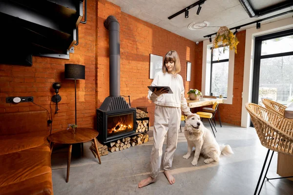 站在客厅里拿着数码平板电脑和她的狗的女人 — 图库照片