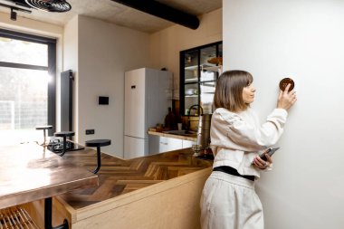 Kadın ev sıcaklığını elektronik termostatla kontrol ediyor