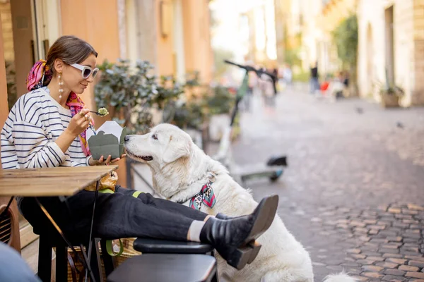 Donna si preoccupa il suo cane mentre mangia pasta all'aperto caffè — Foto Stock