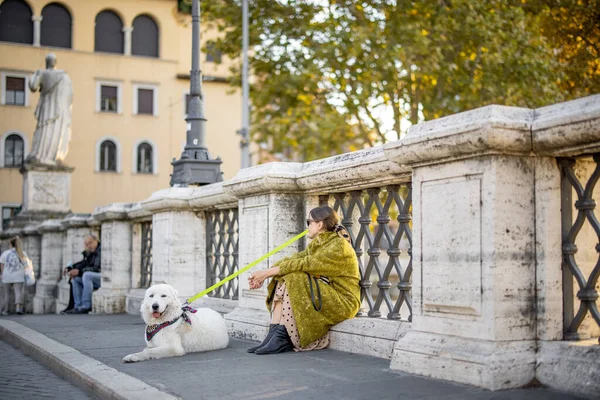 Γυναίκα με το άσπρο σκυλί της να κάθεται στο δρόμο στη Ρώμη. — Φωτογραφία Αρχείου