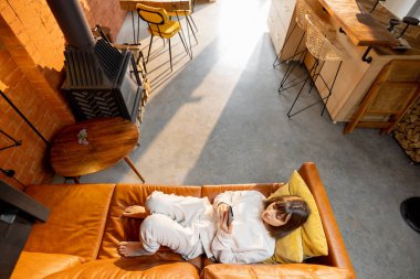 Kanepede uzanmış ve evde telefon kullanan bir kadın.