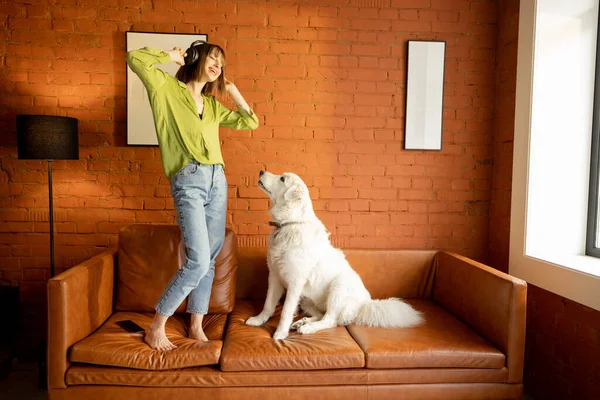 女人和她的狗在家里的沙发上玩乐 — 图库照片