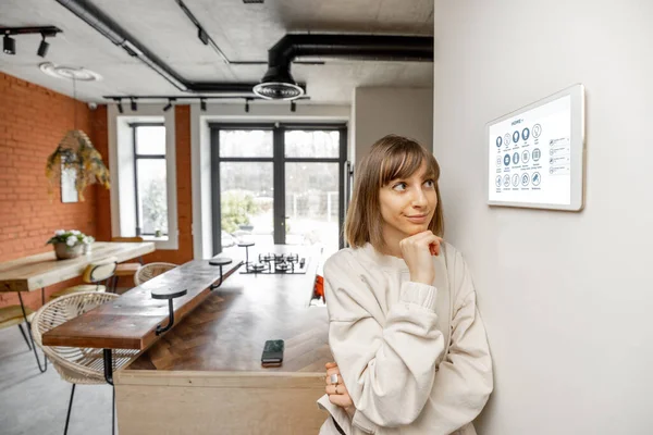 Kvinna styra hem enheter med digital smart panel monterad på väggen — Stockfoto