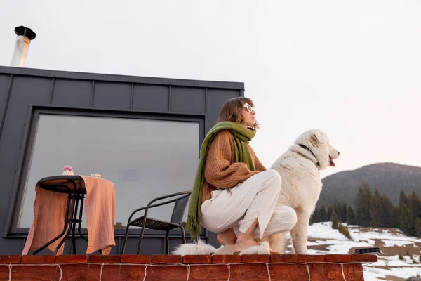 Žena se svým psem odpočívá na terase malého domku na přírodě — Stock fotografie