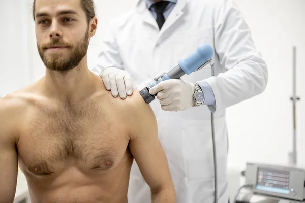 Legen påfører sjokkbølgeterapi på menn skulder – stockfoto