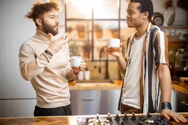 Двоє чоловіків розмовляють і п'ють каву на кухні вдома — стокове фото