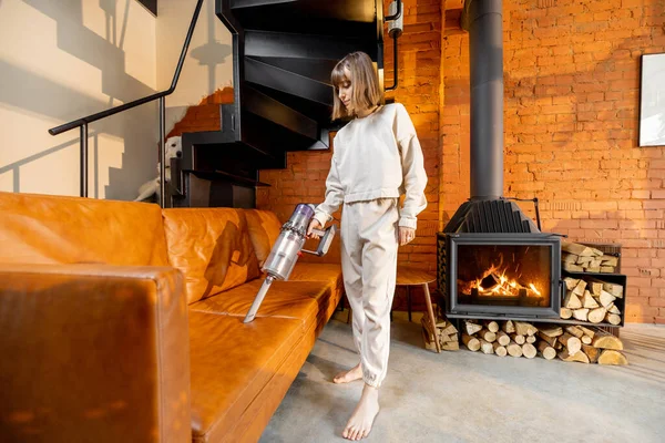 Kablosuz elektrikli süpürgeyle kanepeyi süpüren kadın.