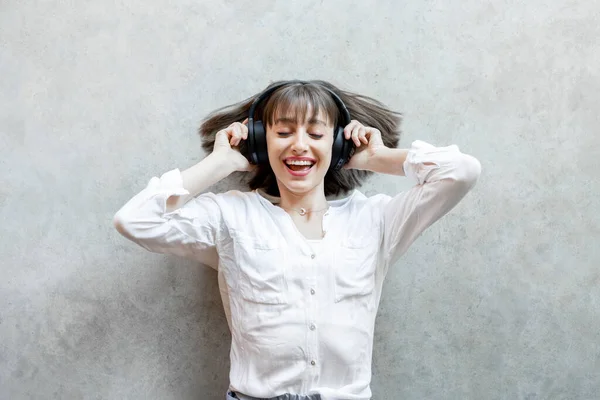 Vrouw die luistert naar de muziek in draadloze hoofdtelefoon op de achtergrond — Stockfoto