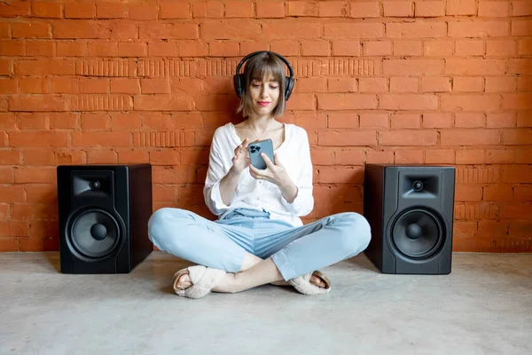 Perempuan mendengarkan musik dengan headphone nirkabel dan speaker — Stok Foto