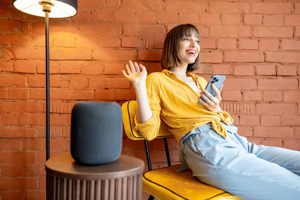 Woman with smart speaker and phone at home — Stock Photo, Image