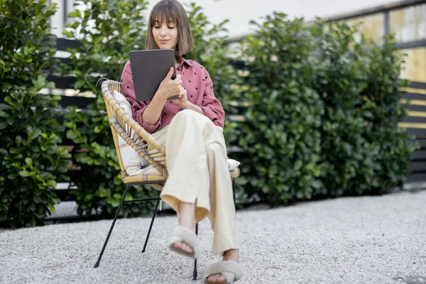 Mujer trabajando en la tableta digital mientras está sentado relajado en el patio trasero — Foto de Stock