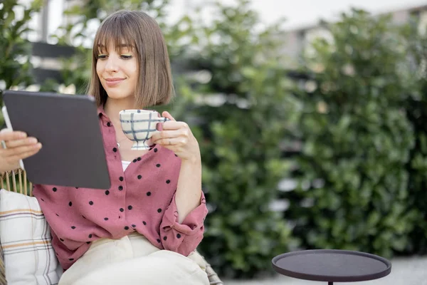 Kadın arka bahçede rahatça otururken dijital tablet üzerinde çalışıyor. — Stok fotoğraf