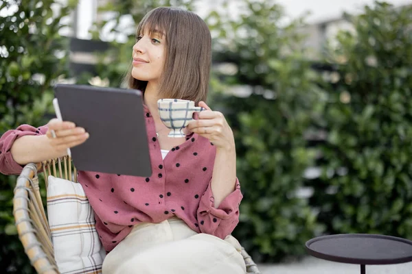 Vrouw werkt op digitale tablet terwijl zitten ontspannen in de achtertuin — Stockfoto
