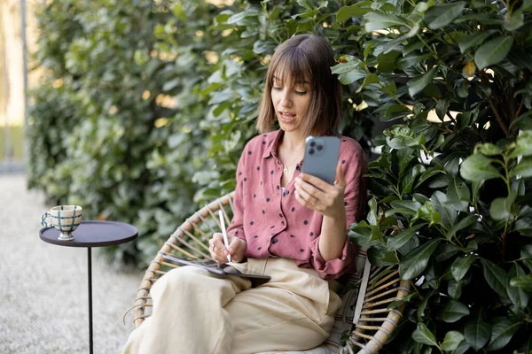 Mujer trabaja en el teléfono inteligente y tableta digital al aire libre — Foto de Stock