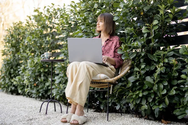 Kvinna arbetar på bärbar dator i trädgården — Stockfoto