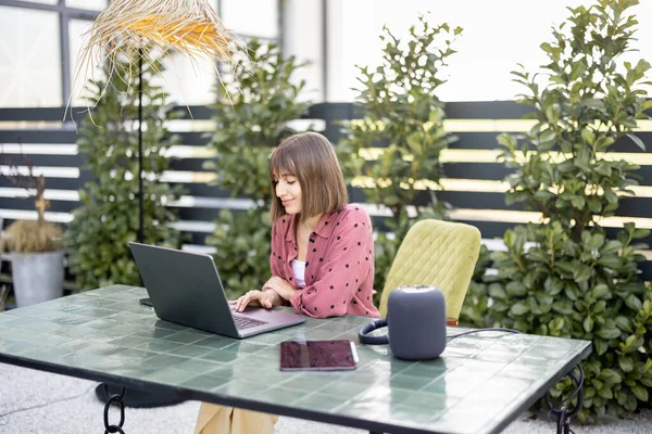 La mujer trabaja en el ordenador portátil en línea en el jardín al aire libre — Foto de Stock