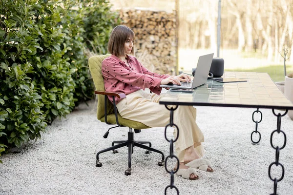 La mujer trabaja en el ordenador portátil en línea en el jardín al aire libre — Foto de Stock