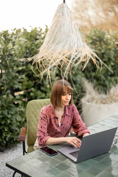 Žena pracuje na notebooku on-line v zahradě venku — Stock fotografie
