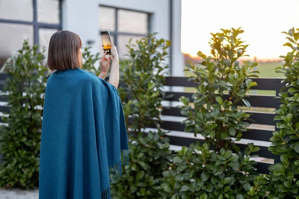 Женщина в клетке фотографирует закат на заднем дворе — стоковое фото