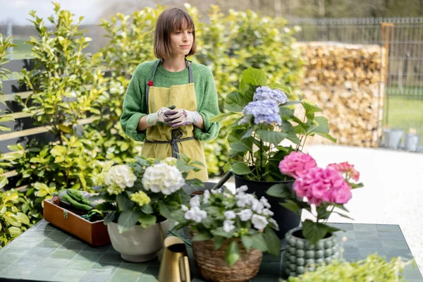 Jovem mulher cuidando de flores no jardim — Fotografia de Stock