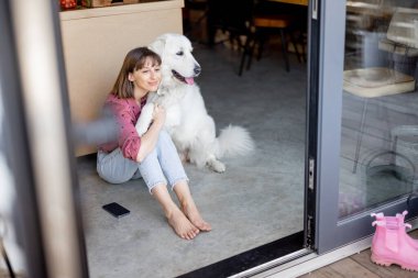 Kadın, tapılası büyük köpeğiyle birlikte evde oturuyor.