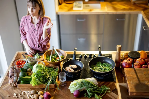 Kvinna matlagning hälsosam och välsmakande mat hemma — Stockfoto