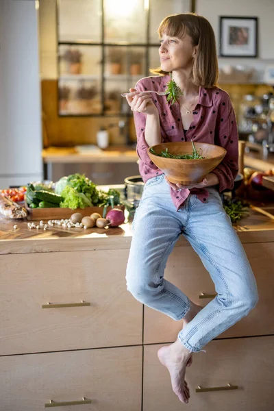 Γυναίκα τρώει υγιεινή σαλάτα στην κουζίνα στο σπίτι — Φωτογραφία Αρχείου