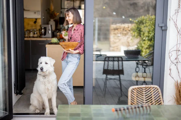Kadın, evdeki terasta sevimli beyaz köpeğiyle birlikte duruyor. — Stok fotoğraf