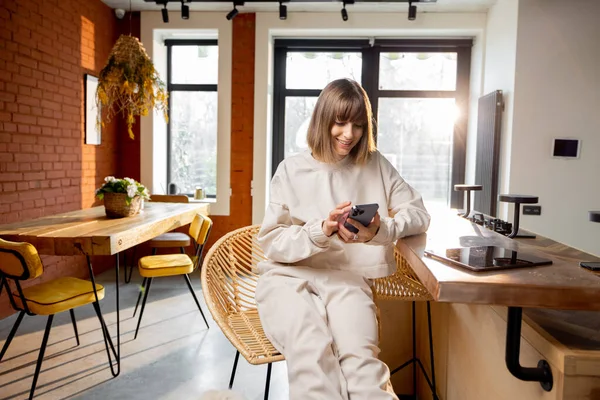 Mujer usando el teléfono mientras está sentado en el apartamento estudio moderno — Foto de Stock
