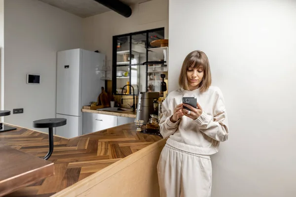 Donna con telefono alla cucina moderna — Foto Stock