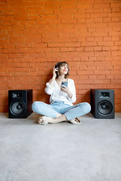 Woman listens to the music with wireless headphones and speakers — Stock Photo, Image