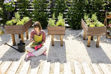 Evdeki sebze bahçesinde telefon kullanan bir kadın.