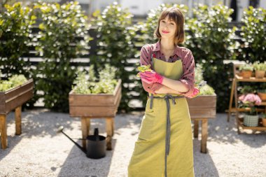 Bahçedeki sebze bahçesinde yeşil önlüklü bir bahçıvanın portresi.