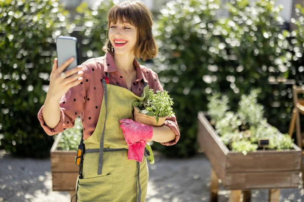 Žena s mobilním telefonem na domácí zahradě — Stock fotografie