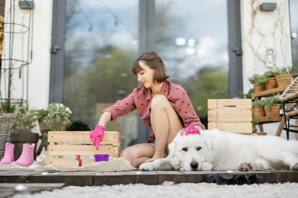 女人画木箱，和狗一起坐在阳台上 — 图库照片