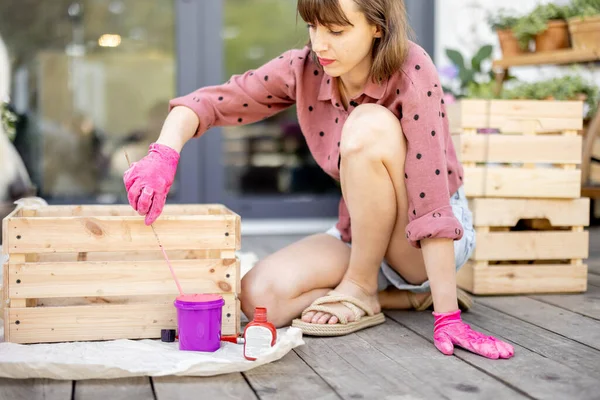 Mujer pintando caja de madera, haciendo algunas tareas domésticas de renovación al aire libre — Foto de Stock