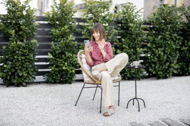 Arka bahçede telefon görüşmesi yapan bir kadın var.