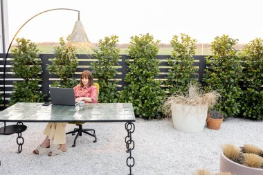 Kadın açık havada internette dizüstü bilgisayarda çalışıyor.