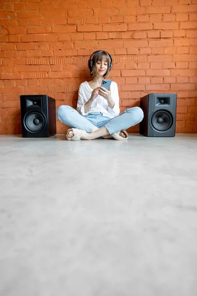 Žena poslouchá hudbu s bezdrátovými sluchátky a reproduktory — Stock fotografie