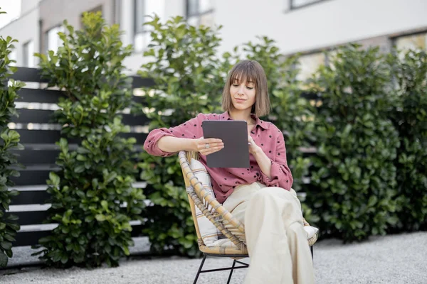 Mujer trabajando en la tableta digital mientras está sentado relajado en el patio trasero — Foto de Stock